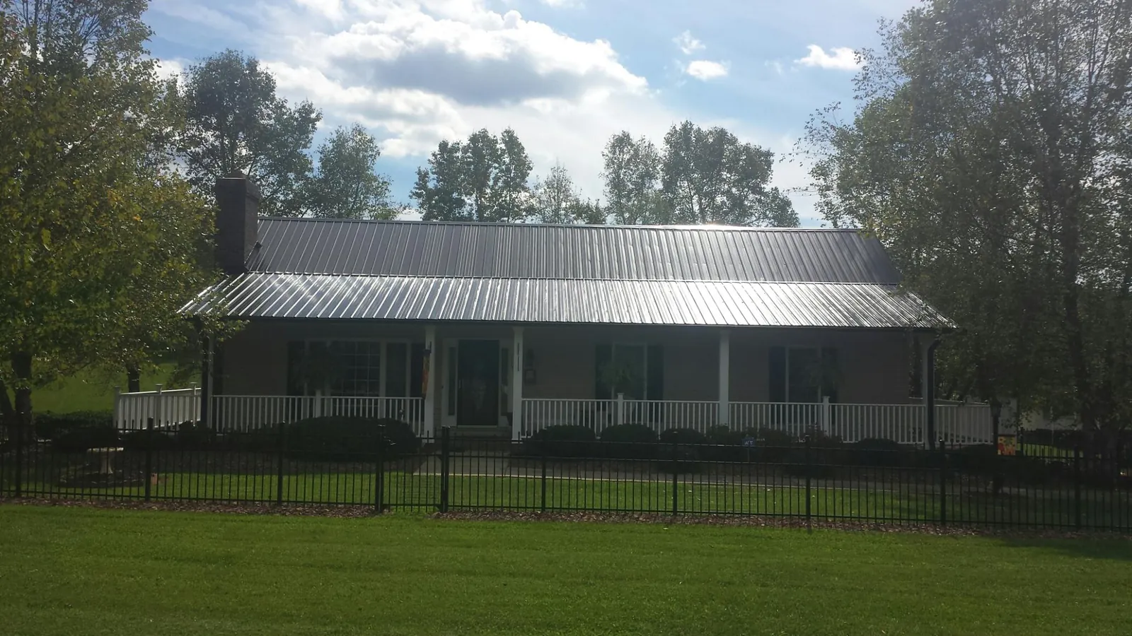 Gray metal roof on a brick ranch with a full width front porch — Gutter Guard Installation work by our crew in Nebraska City
