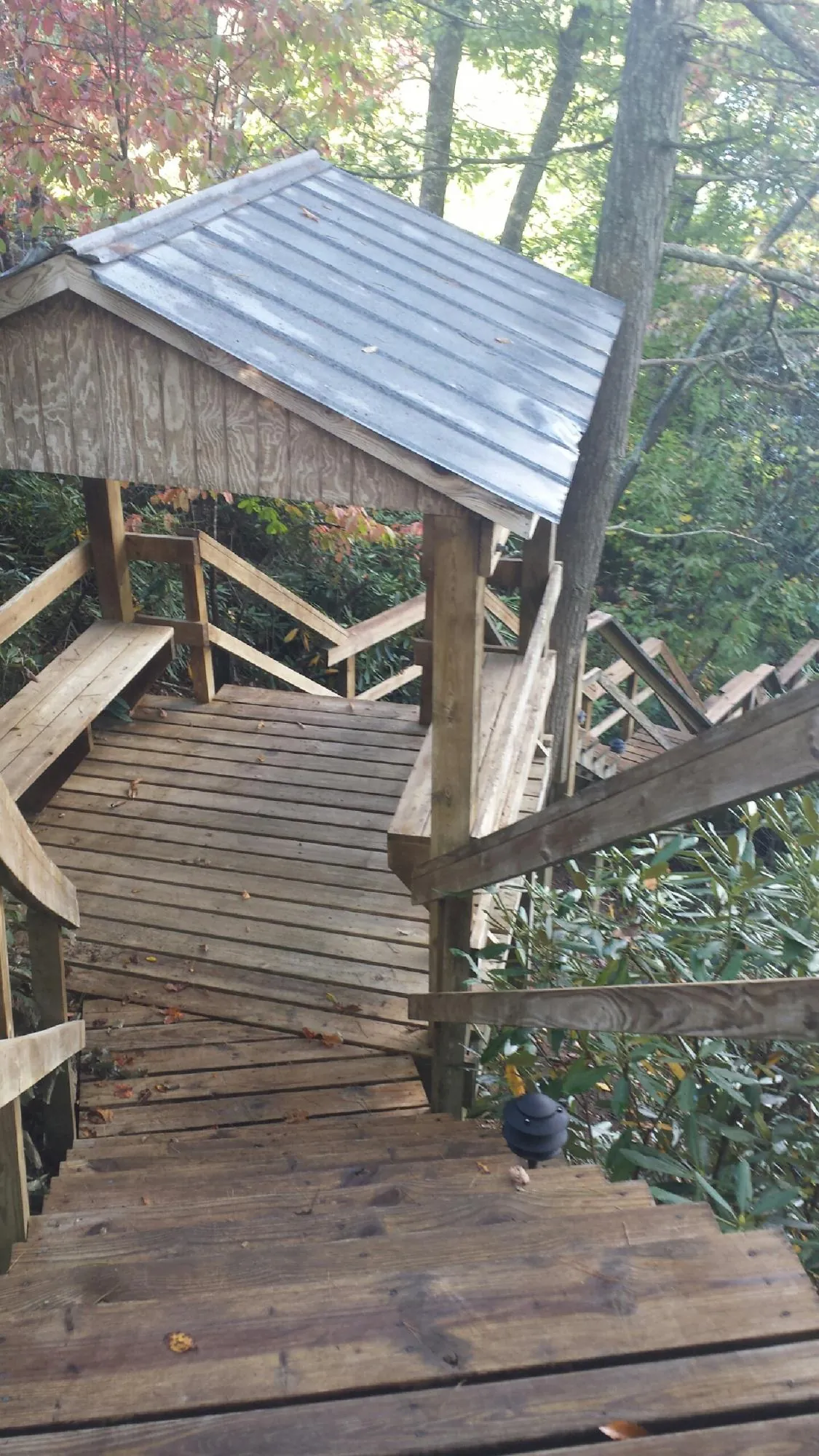 Metal roofed shelter over wooden steps on a wooded walkway — Skylight Repair & Installation work by our crew in Nebraska City