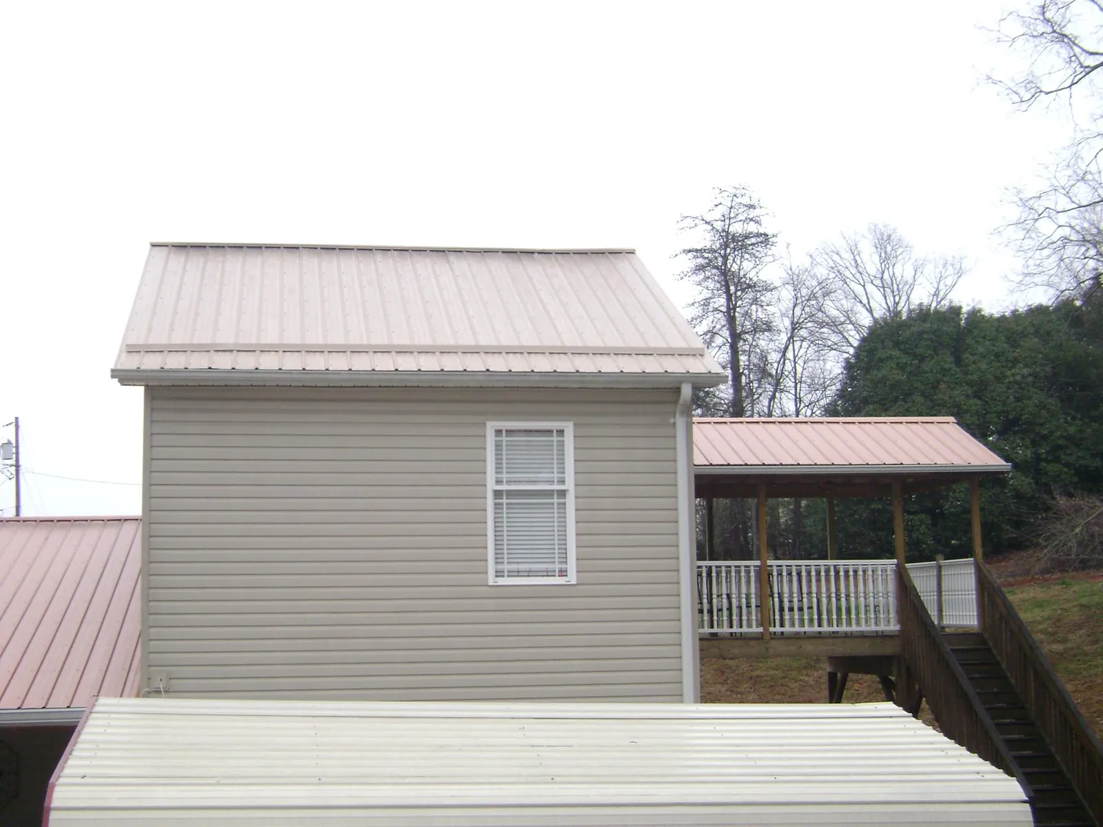 Tan metal roofs on a two story addition and attached porch, from a Roof Replacement job in Nebraska City