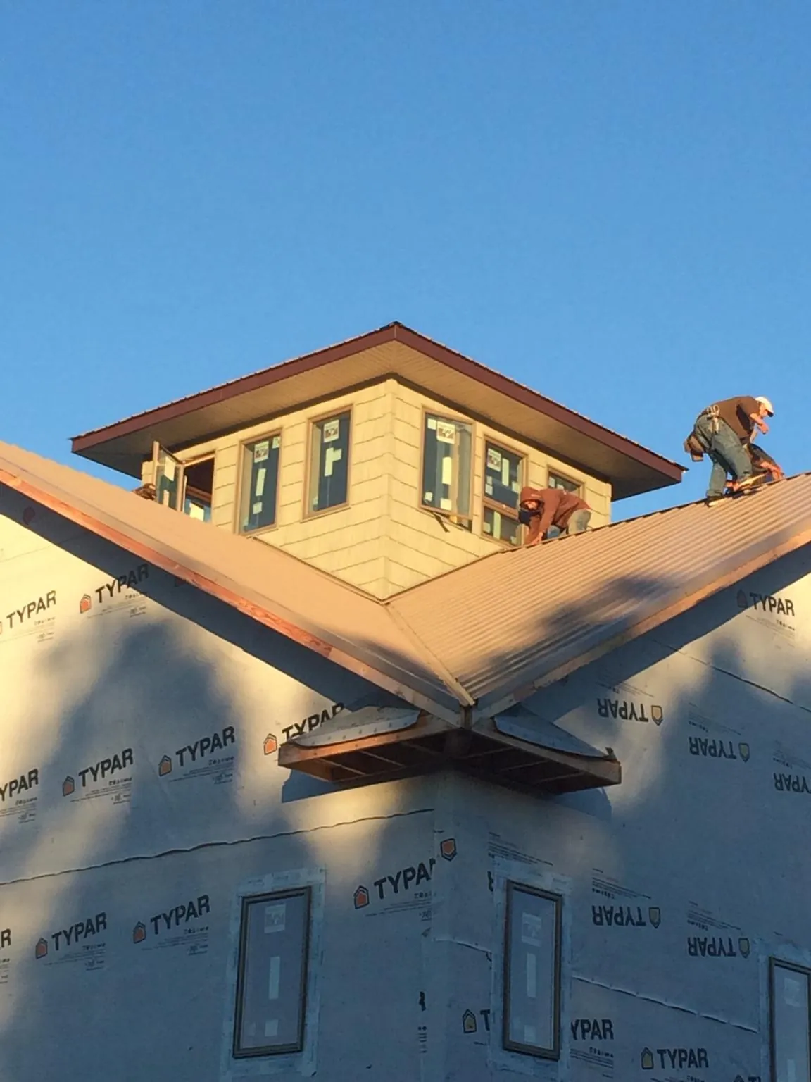 Roofers working around a rooftop cupola on a new metal roof at sunset — Roof Waterproofing in Nebraska City by Roofing Brothers